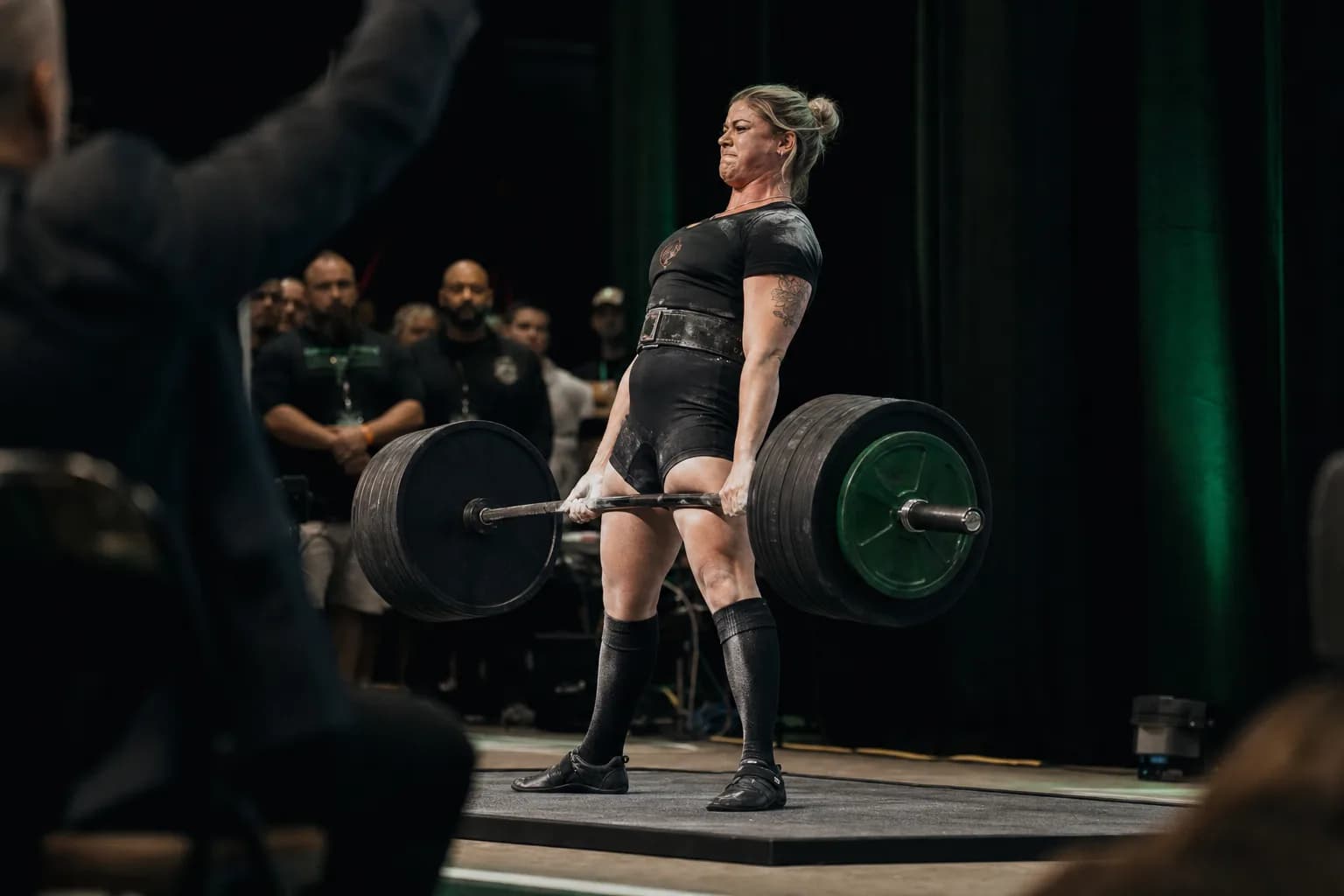 A powerlifter completing a competition deadlift on the platform