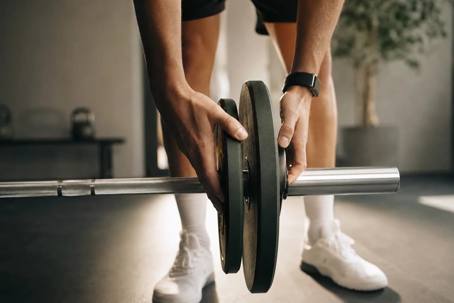 An athlete loading small plates onto a barbell before working sets